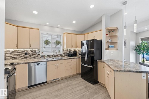 Kitchen featuring wood-finish cabinetry, stainless steel dishwasher, tile backsplash, and recessed lighting - 2109 37 Avenue Nw, Edmonton, AB 
