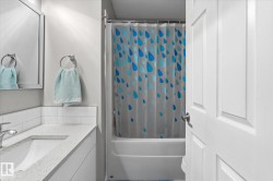 White paneled door, built-in bathtub, and a vanity with an integrated sink and light-toned countertop - 