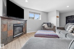 Built-in fireplace with a stone-finish surround, wood-finish mantel, wood-finish flooring, and a recessed ceiling light - 