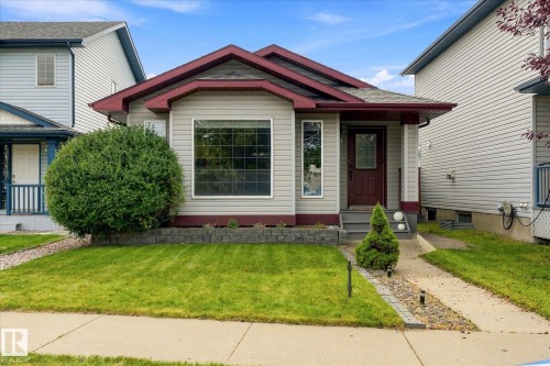 Light-toned siding exterior with a contrasting trim, prominent front window, covered front porch, and a concrete pathway - 2109 37 Avenue Nw, Edmonton, AB 