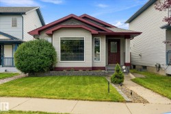 Light-toned siding exterior with a contrasting trim, prominent front window, covered front porch, and a concrete pathway - 