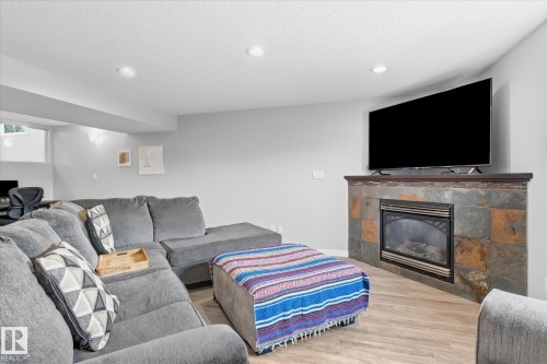 Recessed lighting, wood-finish flooring, and a slate-tiled fireplace with a dark wood mantle - 2109 37 Avenue Nw, Edmonton, AB 