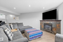 Recessed lighting, wood-finish flooring, and a slate-tiled fireplace with a dark wood mantle - 