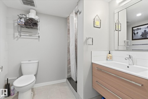 Vanity with wood-finish cabinetry and chrome hardware, subway tile backsplash, and a large wall-mounted mirror - 2109 37 Avenue Nw, Edmonton, AB 