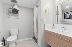 Vanity with wood-finish cabinetry and chrome hardware, subway tile backsplash, and a large wall-mounted mirror - 