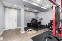 Recessed lighting, wood-finish flooring, light gray wall paint, white trim, and a paneled interior door - 