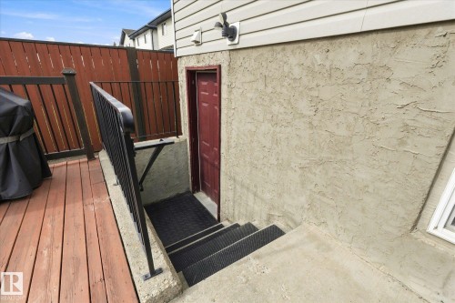 Wood-finish deck with a privacy fence, concrete steps, and a dark red exterior door - 2109 37 Avenue Nw, Edmonton, AB 