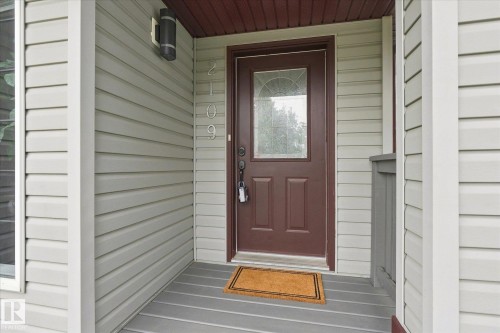 Entryway featuring a brown door with decorative glass insert, light-colored horizontal siding, and a covered porch - 2109 37 Avenue Nw, Edmonton, AB 