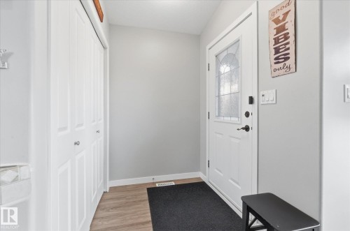 Entryway featuring wood-finish flooring, a white paneled door with decorative glass, and a bi-fold closet with white paneled doors - 2109 37 Avenue Nw, Edmonton, AB 