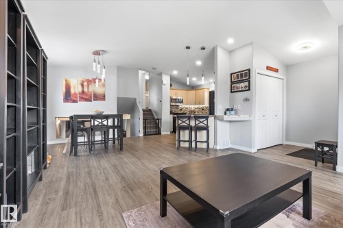 Open concept living space with wood-finish flooring, recessed lighting, and a contemporary pendant fixture - 2109 37 Avenue Nw, Edmonton, AB 