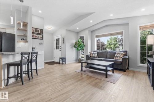 Light wood-finish flooring, recessed lighting, built-in shelving, and large windows - 2109 37 Avenue Nw, Edmonton, AB 