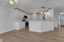 Kitchen featuring white cabinetry, stainless steel appliances, a breakfast bar, and wood-finish flooring - 