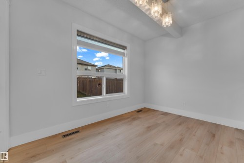 Wood-finish flooring, a contemporary chandelier, white walls, and a large window - 3003 25 Avenue Nw, Edmonton, AB 