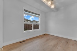 Wood-finish flooring, a contemporary chandelier, white walls, and a large window - 