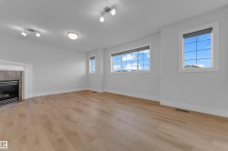 Light wood-finish flooring, multiple large windows, recessed lighting, ceiling-mounted light fixture, and a built-in fireplace with a tile surround - 