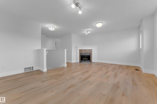 Wood-finish flooring throughout, featuring a fireplace with a wood surround and stone tile - 3003 25 Avenue Nw, Edmonton, AB 