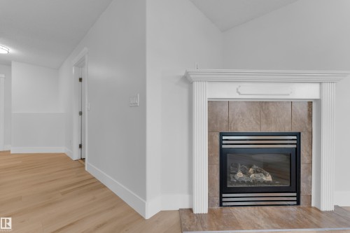 Fireplace with a decorative mantel, tiled surround, and gas insert - 3003 25 Avenue Nw, Edmonton, AB 