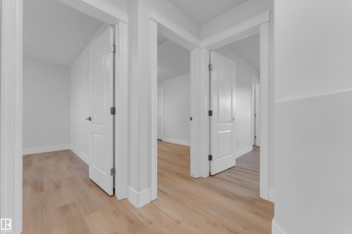 Light wood-finish flooring, white painted walls, and white trim throughout - 3003 25 Avenue Nw, Edmonton, AB 