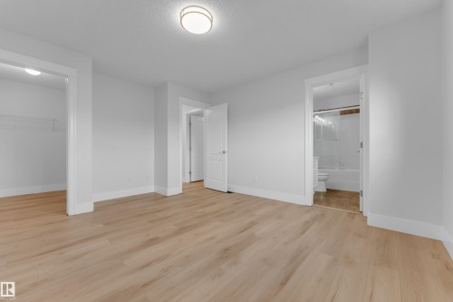 Light wood-finish flooring, white painted walls, and a ceiling-mounted light fixture - 3003 25 Avenue Nw, Edmonton, AB 