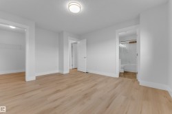 Light wood-finish flooring, white painted walls, and a ceiling-mounted light fixture - 