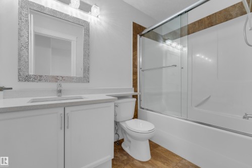 White vanity with integrated sink, chrome faucet, and decorative mirror - 3003 25 Avenue Nw, Edmonton, AB 