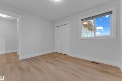 Light wood-finish flooring, white bi-fold closet doors, white trim, and a window with blinds - 