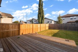 Expansive outdoor deck with natural wood planks, bordered by a privacy fence, and a manicured lawn - 