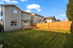 Expansive backyard with a manicured lawn, a full wooden privacy fence, and a wooden deck - 