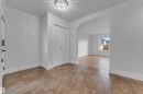 Tiled entryway flooring, crystal flush-mount ceiling light, white bi-fold closet doors, arched doorway, and wood-finish flooring - 3003 25 Avenue Nw, Edmonton, AB 