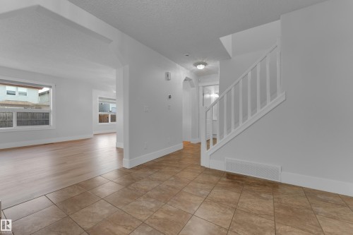 Bright foyer featuring tile flooring, recessed lighting, and a graceful staircase with white balusters - 3003 25 Avenue Nw, Edmonton, AB 