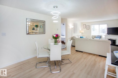 Light wood-finish flooring, recessed lighting, and a modern chandelier with circular rings - #201 1070 Mcconachie Bv Nw, Edmonton, AB 