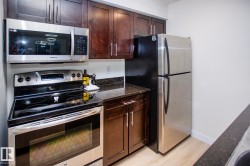 Stainless steel appliances, wood-finish cabinetry, dark countertops, built-in microwave, and wood-finish flooring - 