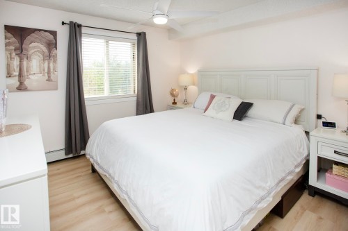 Recessed lighting, wood-finish flooring, white paneled headboard, white window blinds, and a white ceiling fan - #201 1070 Mcconachie Bv Nw, Edmonton, AB 