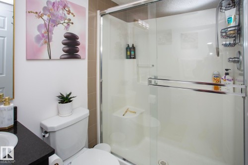 Walk-in shower with a glass enclosure, white shower base, and integrated shelving - #201 1070 Mcconachie Bv Nw, Edmonton, AB 