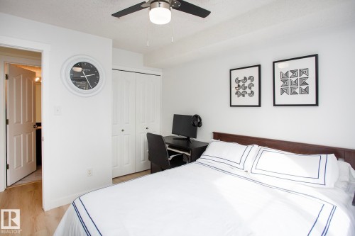 Wood-finish flooring, ceiling fan, white bi-fold closet doors, and a wood headboard - #201 1070 Mcconachie Bv Nw, Edmonton, AB 