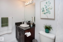 Vanity with a dark countertop and undermount sink, large wall-mounted mirror, and contemporary light fixture - 