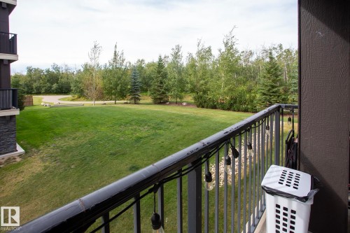 Balcony featuring a metal railing and a partial stone facade - #201 1070 Mcconachie Bv Nw, Edmonton, AB 