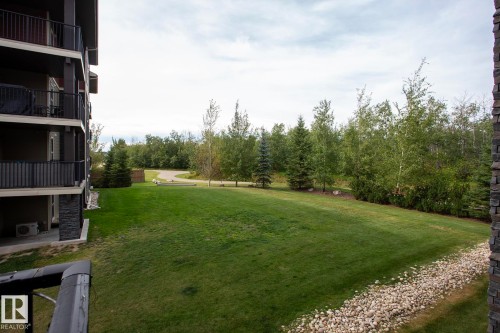 Expansive green space with mature trees, gravel landscaping, and a paved pathway - #201 1070 Mcconachie Bv Nw, Edmonton, AB 