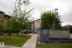 Building exterior featuring a stone-clad monument sign, mature trees, and a paved walkway - 