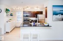 Kitchen featuring dark wood cabinetry, stainless steel appliances, a black countertop breakfast bar, and track lighting - #201 1070 Mcconachie Bv Nw, Edmonton, AB 