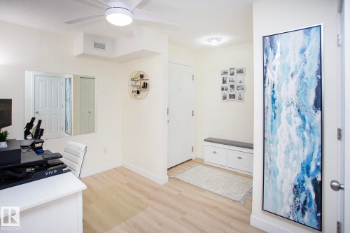 Light wood-finish flooring throughout, complemented by a ceiling fan with integrated lighting - #201 1070 Mcconachie Bv Nw, Edmonton, AB 