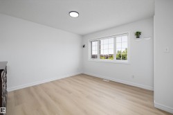 Light-filled interior featuring expansive window, wood-finish flooring, white baseboards, and a flush-mount ceiling light - 