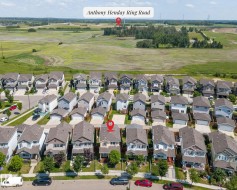 Aerial perspective showcasing a residential street with detached homes, each featuring individual driveways and front yards - 