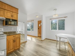 Kitchen featuring wood cabinetry, stone-finish countertops, and a white tile backsplash - 
