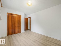 Light-toned wood-finish flooring, white walls, wood bi-fold closet doors, and overhead flush-mount lighting - 