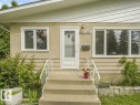 Stucco exterior with horizontal siding accents, concrete steps with white metal railings, and a white storm door - 16428 88 Avenue Nw, Edmonton, AB 
