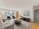 Hardwood-style flooring throughout, expansive window providing natural light, white wall finishes, and a contemporary front entry door - 16428 88 Avenue Nw, Edmonton, AB 
