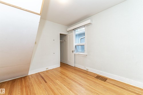 Hardwood flooring, painted white walls, white trim, single window, and a built-in closet with hanging rod - 10930 80 Avenue Nw, Edmonton, AB 