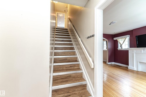 Wood-finish staircase with white risers and handrail - 10930 80 Avenue Nw, Edmonton, AB 