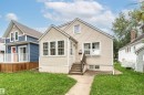 Cream-colored siding exterior with a pitched roof, front entry stairs, a concrete walkway, and a manicured lawn - 10930 80 Avenue Nw, Edmonton, AB 